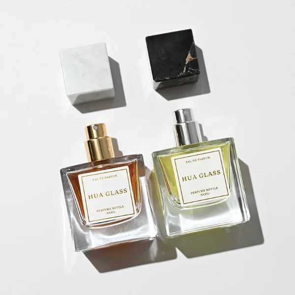 HUA0226 perfume bottle, square transparent glass body with thick base, 30 ml, 50 ml, or 100 ml liquid, square natural stone cap with customizable color and organic stone texture, brand label applied on bottle, modern luxurious fashion design, ideal for gifting and daily use.