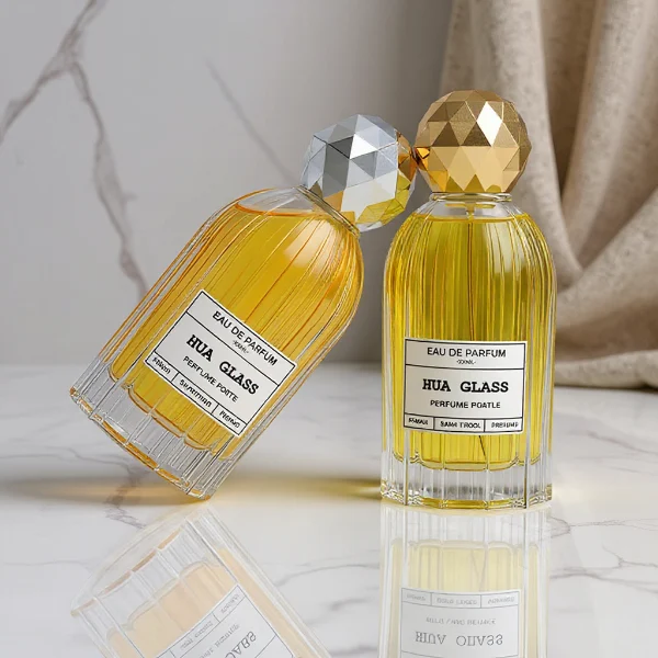 HUA0229 perfume bottle, cylindrical transparent glass body with ribbed sides and thick base, 100 ml liquid, faceted geometric sphere plastic cap in gold or silver, brand label applied on bottle, modern luxurious fashion design, ideal for gifting and daily use.