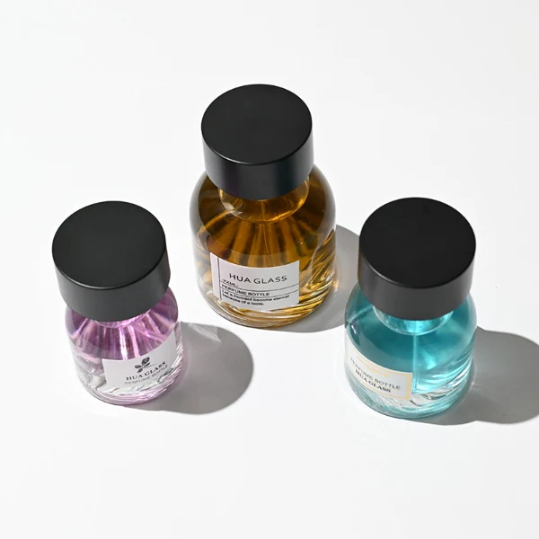 HUA0234 perfume bottle, flattened oval transparent glass body with thick base and smooth rounded contours, 30 ml, 50 ml, or 100 ml liquid, cylindrical plastic cap with flat top, brand label applied on bottle, modern luxurious design, ideal for gifting and daily use.