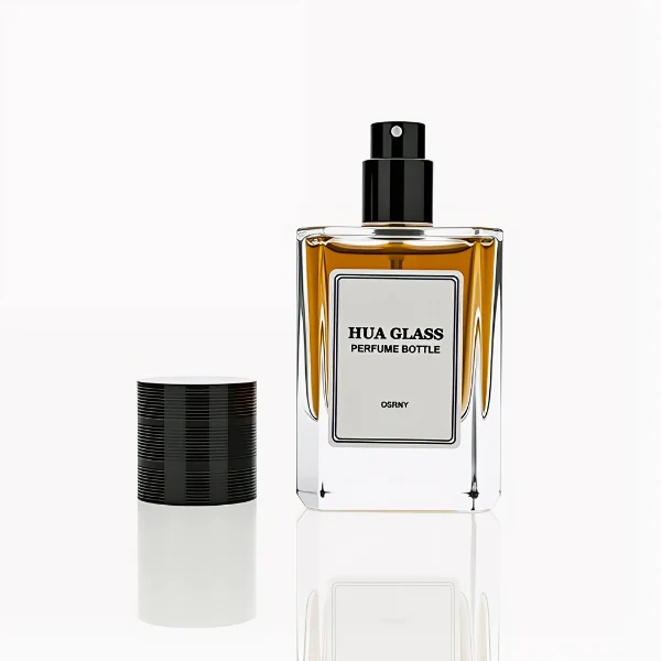HUA0235 perfume bottle, square transparent glass body with thick base, 30 ml, 50 ml, or 100 ml liquid, cylindrical plastic cap with side threading and metallic finish in gold, black, or silver, brand label applied on bottle, modern luxurious design, ideal for gifting and daily use.