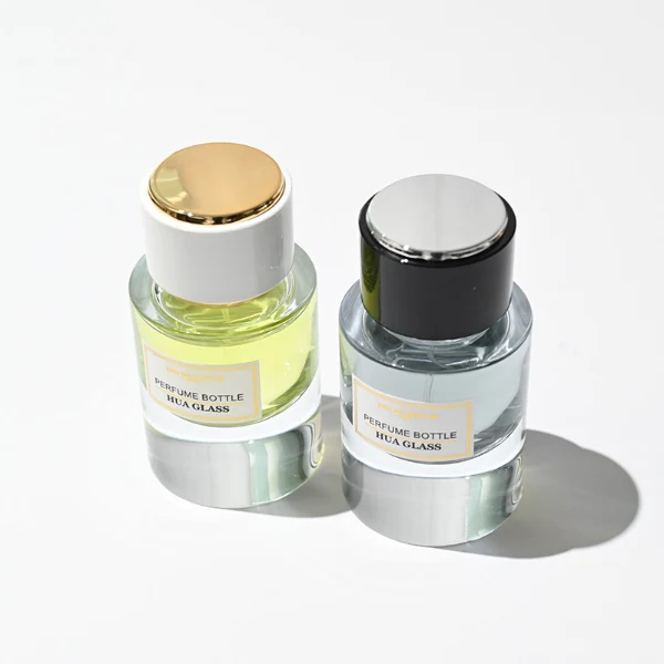 HUA0242 perfume bottle, cylindrical transparent glass body with thick base, 30 ml, 50 ml, or 100 ml liquid, cylindrical plastic cap with black or white side and silver plastic rings on both top and bottom, brand label applied on bottle, modern luxurious design, ideal for gifting and daily use.