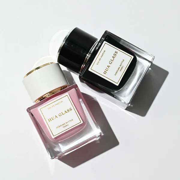 HUA0243 perfume bottle, cylindrical transparent internal spray glass body with thick base, 30 ml, 50 ml, or 100 ml liquid, cylindrical plastic cap with black or white side and gold or silver plastic rings on both top and bottom, brand label applied on bottle, modern luxurious design, ideal for gifting and daily use.