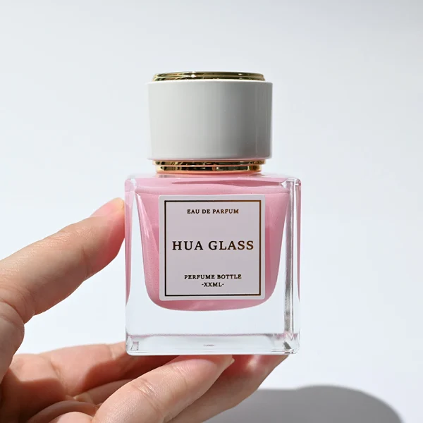 HUA0243 perfume bottle, cylindrical transparent internal spray glass body with thick base, 30 ml, 50 ml, or 100 ml liquid, cylindrical plastic cap with black or white side and gold or silver plastic rings on both top and bottom, brand label applied on bottle, modern luxurious design, ideal for gifting and daily use.