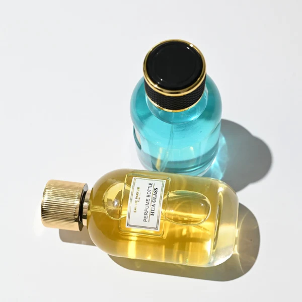 HUA0244 perfume bottle, cylindrical transparent glass body with thick base, 100 ml liquid, cylindrical plastic cap with exterior wrapped in leather or textured pattern, gold-colored bottle neck, brand label applied on bottle, modern luxurious design, ideal for gifting and daily use.