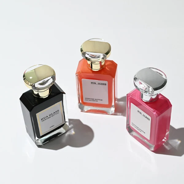 HUA0245 perfume bottle, rectangular transparent glass body with beveled corners and thick base, customizable inner spray colors, 30 ml, 50 ml, or 100 ml liquid, irregular metallic plastic cap with silver or gold side bar details, printed logo label, modern luxury fashion design, ideal for gifting and daily use.