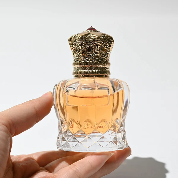 HUA0249 perfume bottle, faceted transparent glass body with thick base, 30 ml, 50 ml, or 100 ml liquid, ornate crown-shaped Zamac cap, brand label applied on bottle, luxurious ornate design, ideal for gifting and daily use.
