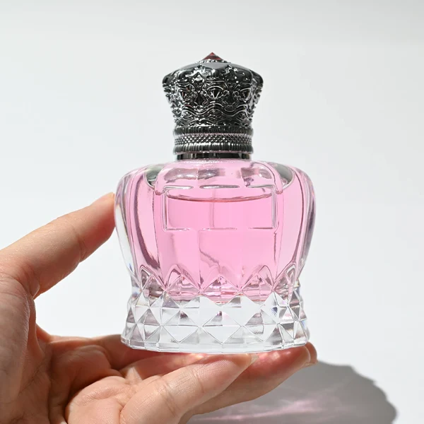 HUA0249 perfume bottle, faceted transparent glass body with thick base, 30 ml, 50 ml, or 100 ml liquid, ornate crown-shaped Zamac cap, brand label applied on bottle, luxurious ornate design, ideal for gifting and daily use.