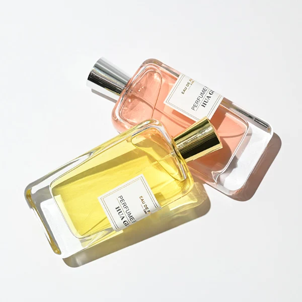HUA0251 perfume bottle, rectangular transparent glass body with thick base, 100 ml liquid, cylindrical plastic cap with smooth high-gloss surface, flat top, straight uniform sides, tightly fitted to bottle neck, brand label applied on bottle, modern luxurious design, ideal for gifting and daily use.