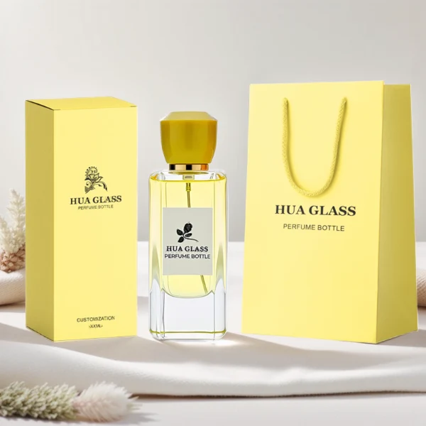 HUA0252 perfume bottle, rectangular transparent glass body with rounded edges and thick base, 50 ml or 80 ml liquid, yellow or red faceted geometric resin cap with smooth glossy finish, gold-colored bottle neck, brand label applied on bottle, modern artistic luxury design, ideal for gifting and daily use.