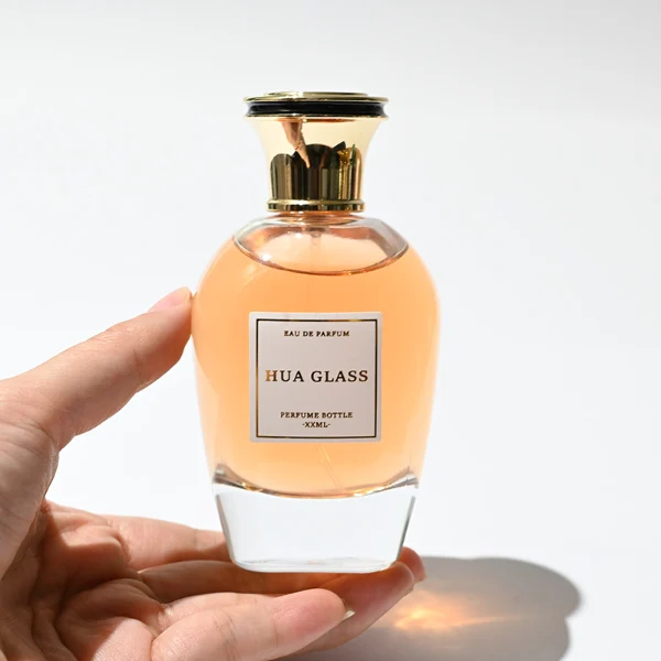 HUA0255 perfume bottle, rounded transparent glass body with soft curved silhouette and thick base, 100 ml liquid, flared Zamac cap with flat top and glossy finish, printed logo label, elegant luxury design, ideal for gifting and daily use.