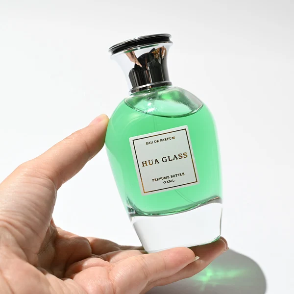 HUA0255 perfume bottle, rounded transparent glass body with soft curved silhouette and thick base, 100 ml liquid, flared Zamac cap with flat top and glossy finish, printed logo label, elegant luxury design, ideal for gifting and daily use.