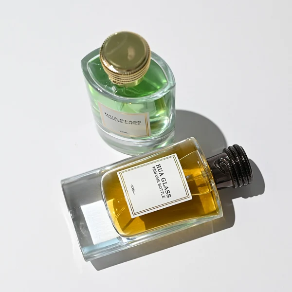 HUA0256 perfume bottle, transparent glass body with rectangular paper bag-inspired silhouette, smooth curved shoulders and oval thick base, 80 ml liquid, cylindrical plastic cap with layered ring texture and metallic glossy finish, printed logo label, modern luxury design, ideal for gifting and daily use.