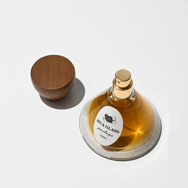 HUA0257 perfume bottle, transparent glass body with wide cone-shaped silhouette and thick rounded base, 30 ml, 50 ml, or 100 ml liquid, rounded wooden cap with matte finish and bowl-shaped silhouette in black or brown color, printed logo label, artistic modern luxury design, ideal for gifting and daily use.