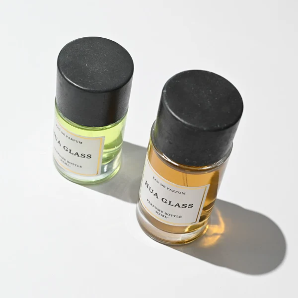 HUA0262 perfume bottle, cylindrical transparent glass body with thick rounded base, 30 ml, 50 ml, or 100 ml liquid, oversized flat cylindrical artificial stone cap with matte texture, printed logo label, modern minimalist luxury design, ideal for gifting and daily use.