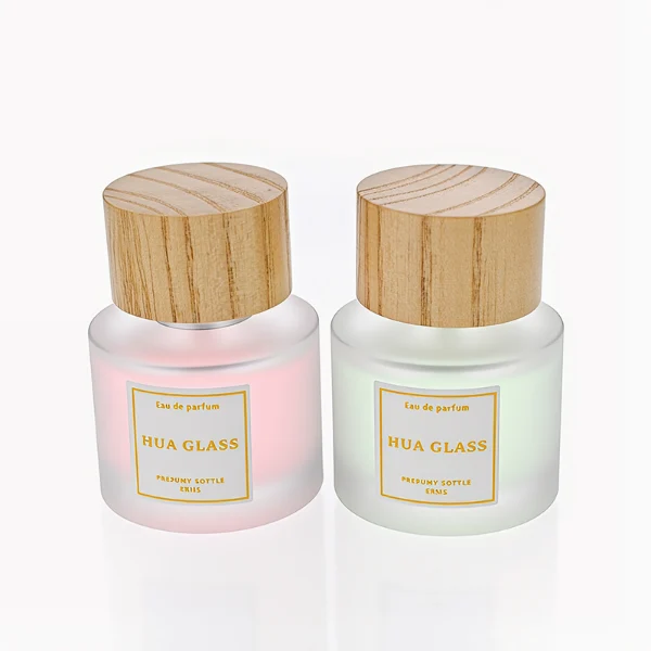 HUA0263 perfume bottle, frosted cylindrical glass body with thick rounded base, 30 ml, 50 ml, or 100 ml liquid, flat cylindrical bamboo cap with natural wood grain texture and silver bottle neck, printed logo label, natural minimalist luxury design, ideal for gifting and daily use.