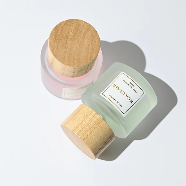 HUA0263 perfume bottle, frosted cylindrical glass body with thick rounded base, 30 ml, 50 ml, or 100 ml liquid, flat cylindrical bamboo cap with natural wood grain texture and silver bottle neck, printed logo label, natural minimalist luxury design, ideal for gifting and daily use.