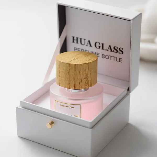 HUA0263 perfume bottle, frosted cylindrical glass body with thick rounded base, 30 ml, 50 ml, or 100 ml liquid, flat cylindrical bamboo cap with natural wood grain texture and silver bottle neck, printed logo label, natural minimalist luxury design, ideal for gifting and daily use.