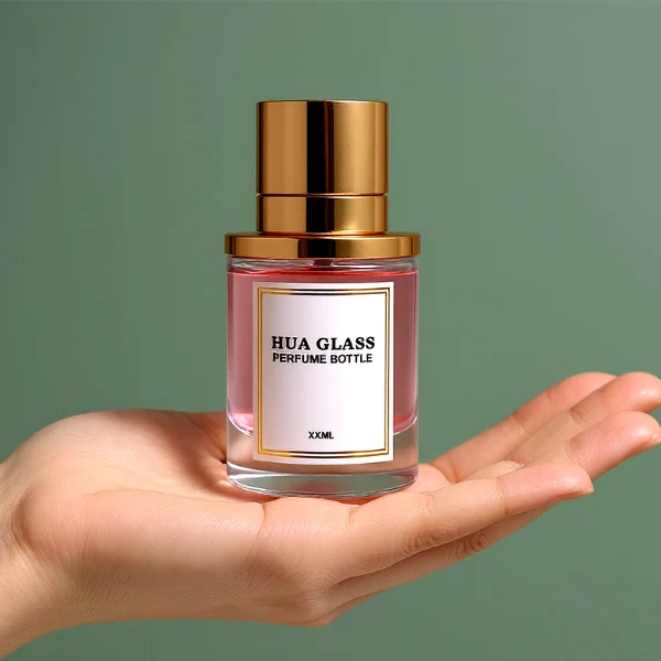 HUA0264 perfume bottle, cylindrical transparent glass body with thick rounded base, 50 ml or 100 ml liquid, stamp-shaped aluminum and magnet cap with glossy black or gold finish, printed logo label, modern luxury minimalist design, ideal for gifting and daily use.