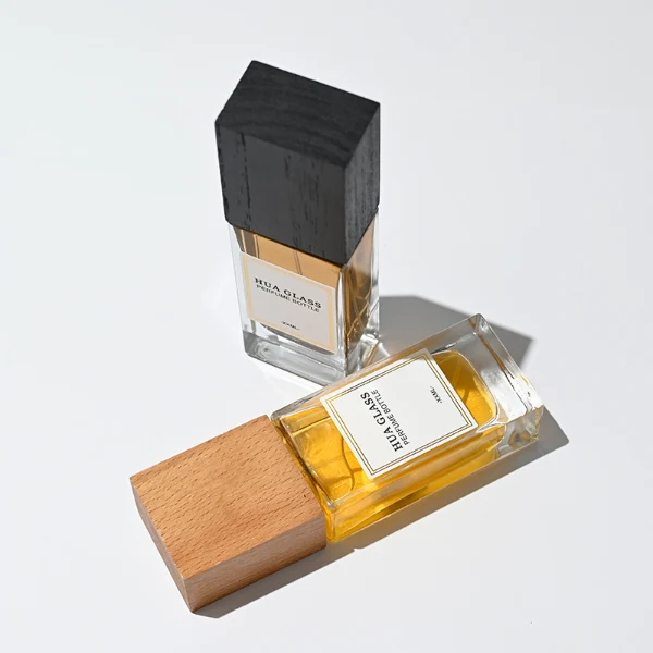 HUA0265 perfume bottle, rectangular transparent glass body with thick weighted base and rounded vertical edges, 30 ml, 50 ml, or 100 ml liquid, oversized rectangular plastic cap in wood-grain brown or matte black finish, printed logo label, modern minimalist luxury design, ideal for gifting and daily use.