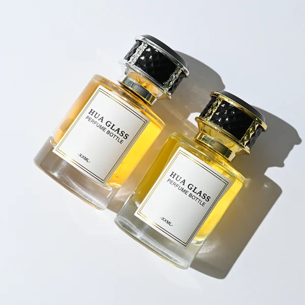 HUA0267 perfume bottle, cylindrical transparent glass body with thick rounded base, 30 ml, 50 ml, or 100 ml liquid, flat cylindrical plastic cap with faceted lattice side texture and gold or silver metallic striped decoration, printed logo label, modern luxury elegance design, ideal for gifting and daily use.
