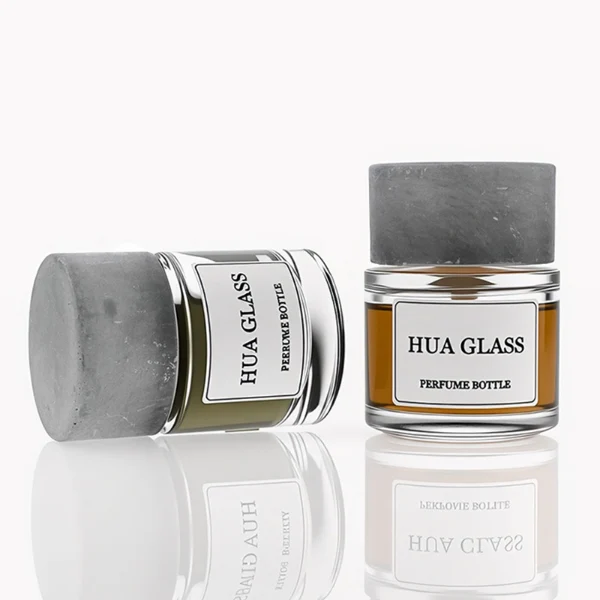 HUA0268 perfume bottle, cylindrical transparent glass body with thick rounded base, 30 ml, 50 ml, or 100 ml liquid, oversized flat cylindrical artificial stone cap with matte stone texture, printed logo label, contemporary minimalist luxury design, ideal for gifting and daily use.
