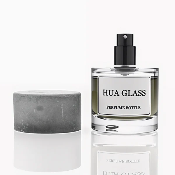 HUA0268 perfume bottle, cylindrical transparent glass body with thick rounded base, 30 ml, 50 ml, or 100 ml liquid, oversized flat cylindrical artificial stone cap with matte stone texture, printed logo label, contemporary minimalist luxury design, ideal for gifting and daily use.