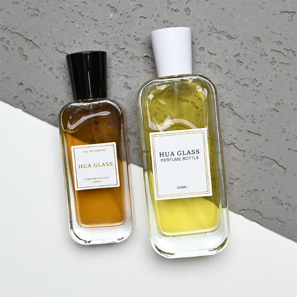 HUA0270 perfume bottle, rounded rectangular transparent glass body with smooth curved corners and thick base, 50 ml or 100 ml liquid, tapered cylindrical plastic cap in glossy black or white finish, printed logo label, modern elegant luxury design, ideal for gifting and daily use.