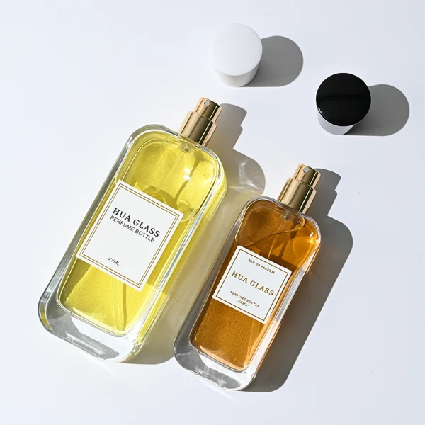 HUA0270 perfume bottle, rounded rectangular transparent glass body with smooth curved corners and thick base, 50 ml or 100 ml liquid, tapered cylindrical plastic cap in glossy black or white finish, printed logo label, modern elegant luxury design, ideal for gifting and daily use.