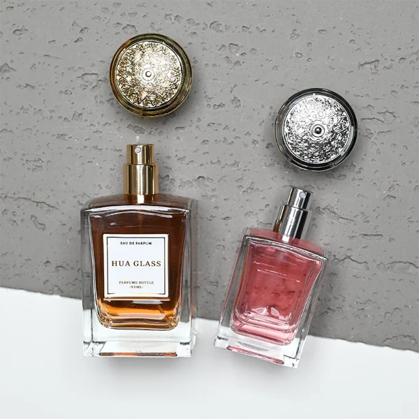 HUA0273 perfume bottle, transparent rectangular glass body with beveled edges and thick base, 50 ml or 100 ml liquid, glossy bowl-shaped plastic cap in silver or gold with matching bottle neck, brand label attached on bottle surface, modern elegant luxury design, ideal for gifting and daily use.