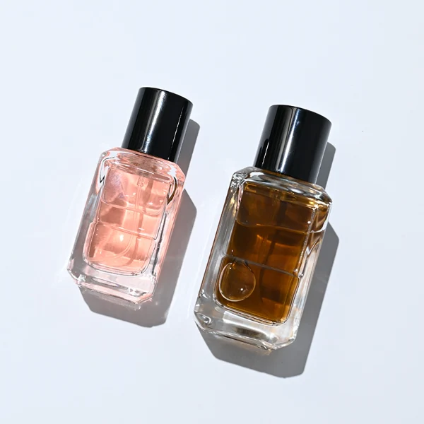 HUA0275 perfume bottle, transparent colorless octagonal glass body with beveled edges and thick base, 30 ml or 50 ml liquid, glossy black cylindrical plastic cap with flat top, aluminum label/sticker attached on bottle surface, modern minimalist luxury design, ideal for gifting and daily use.