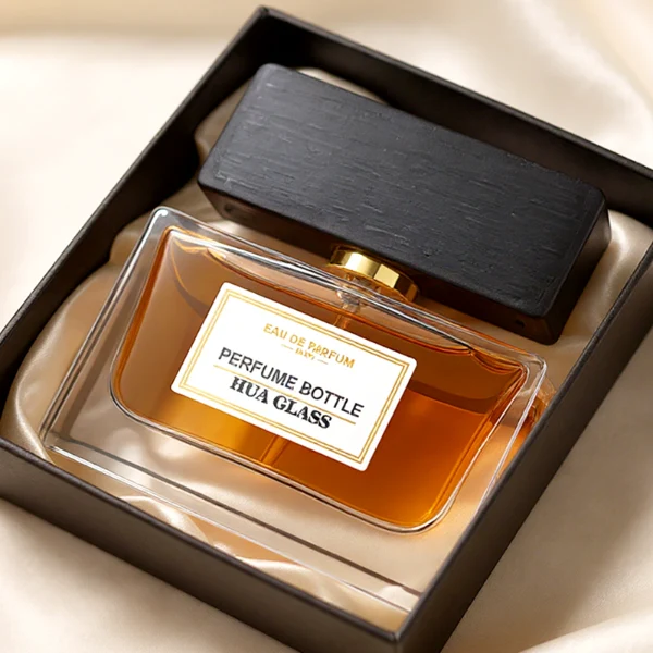 HUA0277 perfume bottle, transparent colorless rectangular glass body with thick base and straight edges, 30 ml, 50 ml, or 100 ml liquid, wide flat rectangular wooden cap in black or natural wood finish with gold bottle neck, printed label attached on bottle surface, modern minimalist luxury design, ideal for gifting and daily use.