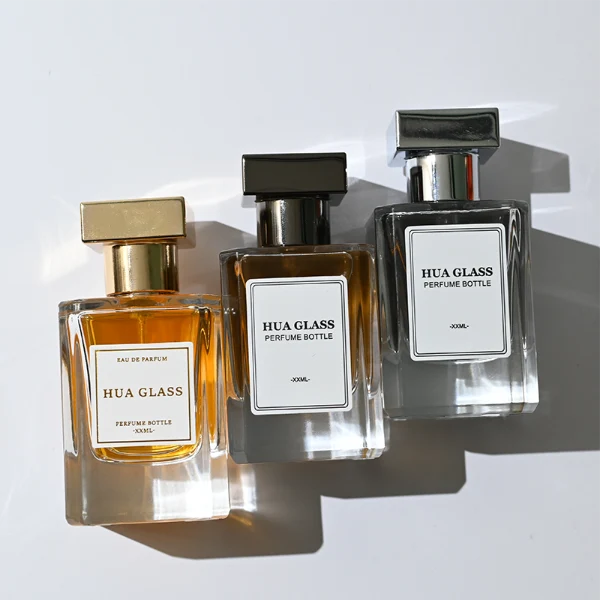 HUA0278 perfume bottle, transparent colorless rectangular glass body with angular edges and thick base, 30 ml, 50 ml, or 100 ml liquid, glossy black or silver square Zamac cap with matching bottle neck, printed label attached on bottle surface, modern masculine luxury design, ideal for gifting and daily use.