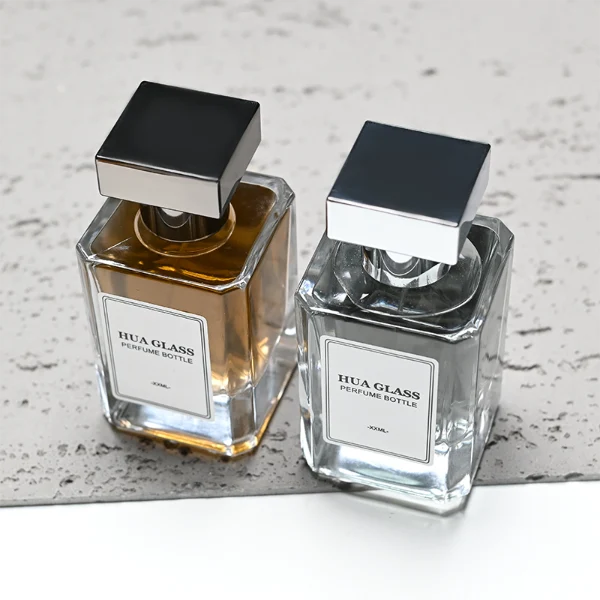HUA0278 perfume bottle, transparent colorless rectangular glass body with angular edges and thick base, 30 ml, 50 ml, or 100 ml liquid, glossy black or silver square Zamac cap with matching bottle neck, printed label attached on bottle surface, modern masculine luxury design, ideal for gifting and daily use.