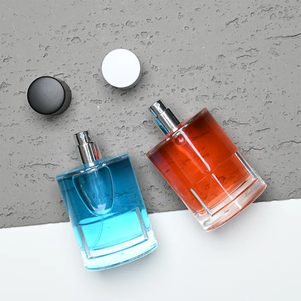 HUA0280 perfume bottle, cylindrical transparent glass body with thick base, 100 ml liquid, glossy flat cylindrical plastic cap in black or white, aluminum label/sticker attached on bottle surface, modern minimalist fashion design, ideal for gifting and daily use.