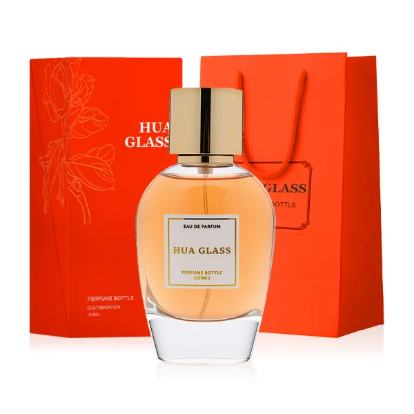 HUA0282 perfume bottle, rounded transparent glass body with thick clear base and customizable transparent colors, 100 ml liquid, glossy cylindrical Zamac cap in silver or gold finish with matching bottle neck, gold-bordered label attached on bottle surface, modern elegant luxury design, ideal for gifting and daily use.