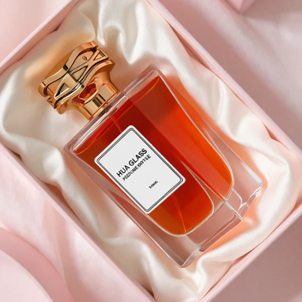 HUA0284 perfume bottle, rectangular transparent colorless glass body with thick base and beveled edges, 100 ml liquid, cylindrical glossy plastic cap with wave-pattern side texture in gold or rose gold finish, printed label attached on bottle surface, modern luxurious fashion design, ideal for gifting and daily use.