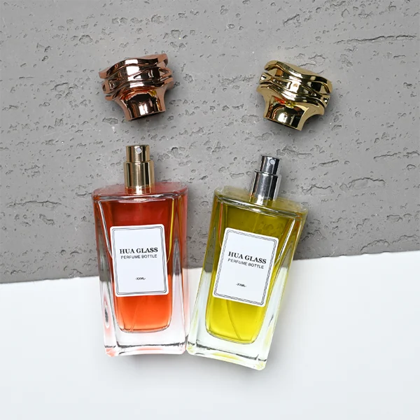 HUA0284 perfume bottle, rectangular transparent colorless glass body with thick base and beveled edges, 100 ml liquid, cylindrical glossy plastic cap with wave-pattern side texture in gold or rose gold finish, printed label attached on bottle surface, modern luxurious fashion design, ideal for gifting and daily use.