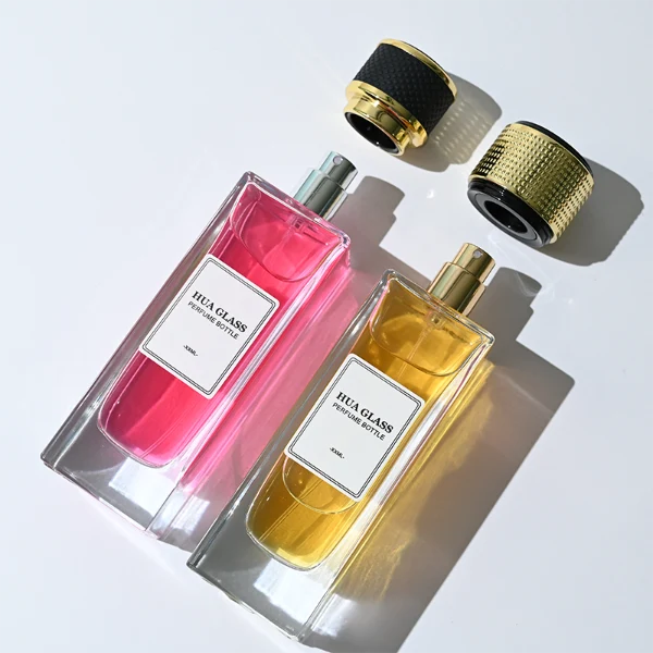 HUA0285 perfume bottle, tall rectangular transparent colorless glass body with thick base and flat sides, label attached on bottle surface, 100 ml liquid, cylindrical plastic cap with white or gold mesh-textured surface and gold or black rings on both ends, modern minimalist luxury design, ideal for gifting and daily use.