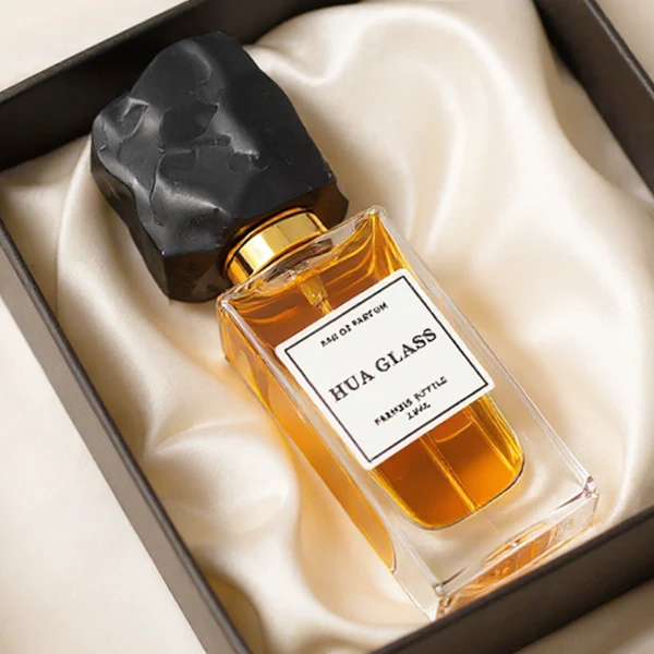 HUA0286 perfume bottle, rectangular transparent colorless glass body with thick base and beveled edges, 30 ml, 50 ml, or 100 ml liquid, irregular natural stone cap with raw textured surface and gold bottle neck, printed label attached on bottle surface, modern artistic luxury design, ideal for gifting and daily use.