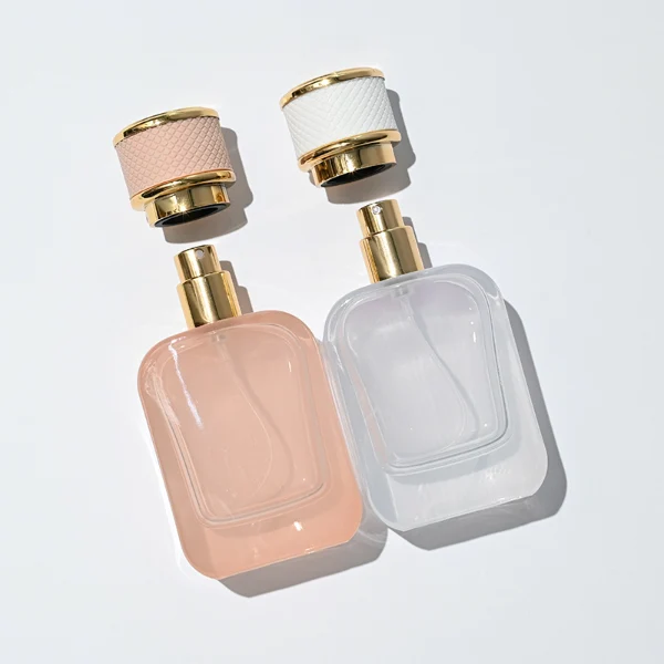 HUA0288 perfume bottle, rounded rectangular transparent or customizable semi-transparent glass body with thick base, 30 ml, 50 ml, or 100 ml liquid, cylindrical gold plastic cap wrapped with mesh-textured leather and gold bottle neck, gold printed logo on bottle surface, modern luxurious fashion design, ideal for gifting and daily use.