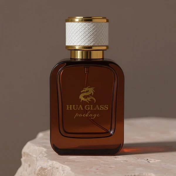 HUA0288 perfume bottle, rounded rectangular transparent or customizable semi-transparent glass body with thick base, 30 ml, 50 ml, or 100 ml liquid, cylindrical gold plastic cap wrapped with mesh-textured leather and gold bottle neck, gold printed logo on bottle surface, modern luxurious fashion design, ideal for gifting and daily use.