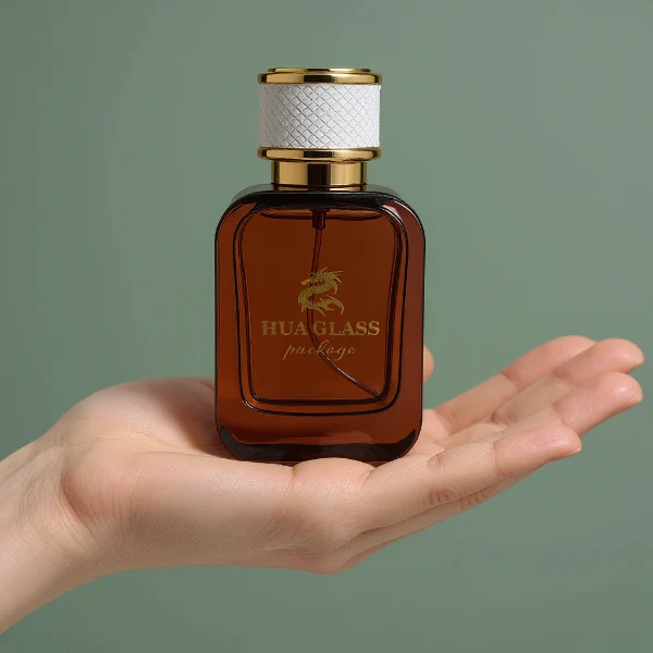HUA0288 perfume bottle, rounded rectangular transparent or customizable semi-transparent glass body with thick base, 30 ml, 50 ml, or 100 ml liquid, cylindrical gold plastic cap wrapped with mesh-textured leather and gold bottle neck, gold printed logo on bottle surface, modern luxurious fashion design, ideal for gifting and daily use.