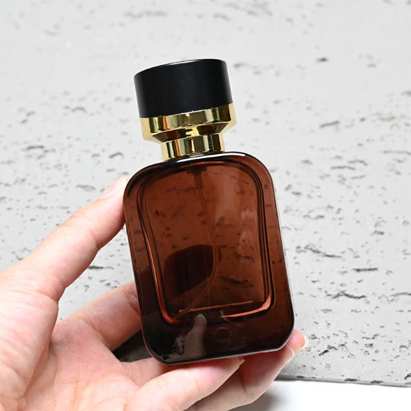 HUA0289 perfume bottle, rounded rectangular semi-transparent black or red glass body with thick base and smooth edges, 30 ml, 50 ml, or 100 ml liquid, black cylindrical plastic cap with diagonal gold accent and gold bottle neck, gold printed logo on bottle surface, modern luxurious fashion design, ideal for gifting and daily use.