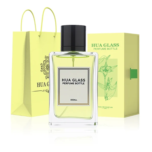 HUA0291 perfume bottle, rectangular transparent colorless glass body with thick base and beveled edges, 100 ml liquid, glossy cylindrical aluminum cap in gold or black finish, printed label attached on bottle surface, modern minimalist luxury design, ideal for gifting and daily use.