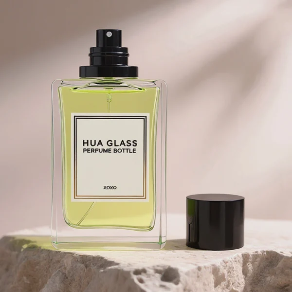 HUA0291 perfume bottle, rectangular transparent colorless glass body with thick base and beveled edges, 100 ml liquid, glossy cylindrical aluminum cap in gold or black finish, printed label attached on bottle surface, modern minimalist luxury design, ideal for gifting and daily use.