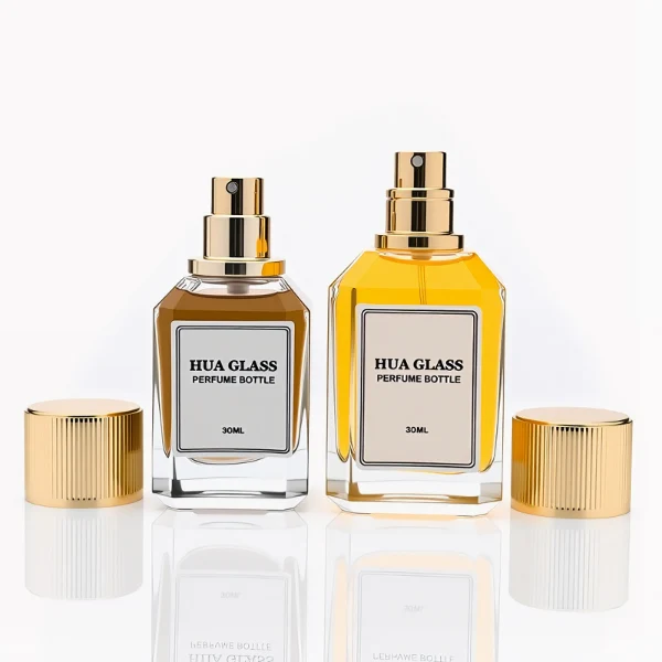 HUA0292 perfume bottle, transparent colorless octagonal beveled glass body with thick base and angled faceted edges, 30 ml, 50 ml, or 100 ml liquid, glossy gold cylindrical aluminum cap with matching gold bottle neck, printed label attached on bottle surface, modern elegant luxury design, ideal for gifting and daily use.
