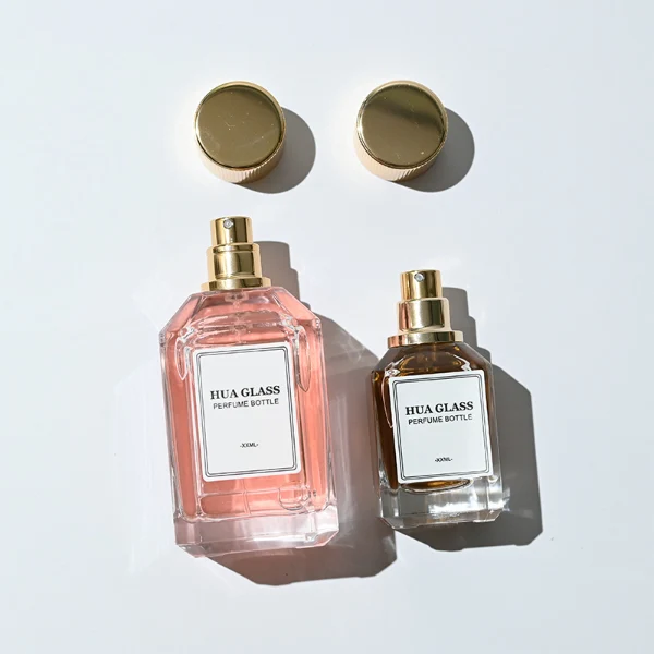 HUA0292 perfume bottle, transparent colorless octagonal beveled glass body with thick base and angled faceted edges, 30 ml, 50 ml, or 100 ml liquid, glossy gold cylindrical aluminum cap with matching gold bottle neck, printed label attached on bottle surface, modern elegant luxury design, ideal for gifting and daily use.