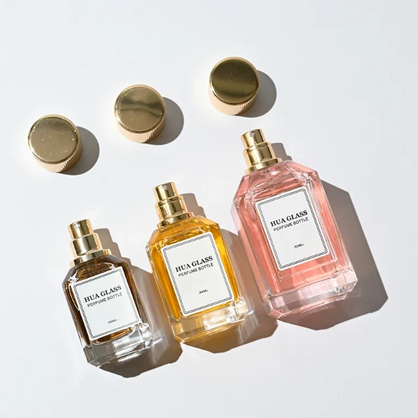 HUA0292 perfume bottle, transparent colorless octagonal beveled glass body with thick base and angled faceted edges, 30 ml, 50 ml, or 100 ml liquid, glossy gold cylindrical aluminum cap with matching gold bottle neck, printed label attached on bottle surface, modern elegant luxury design, ideal for gifting and daily use.