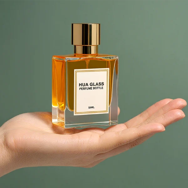 HUA0294 perfume bottle, square transparent colorless glass body with thick base and beveled edges, 50 ml liquid, glossy cylindrical Zamac cap in black, gold, or silver finish with matching bottle neck, printed label attached on bottle surface, modern minimalist luxury design, ideal for gifting and daily use.