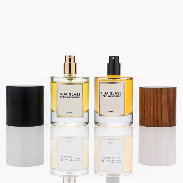 HUA0296 perfume bottle, cylindrical transparent colorless glass body with thick base and smooth rounded silhouette, 30 ml, 50 ml, or 100 ml liquid, cylindrical wooden cap in natural wood or matte black finish, printed label attached on bottle surface, modern minimalist luxury design, ideal for gifting and daily use.